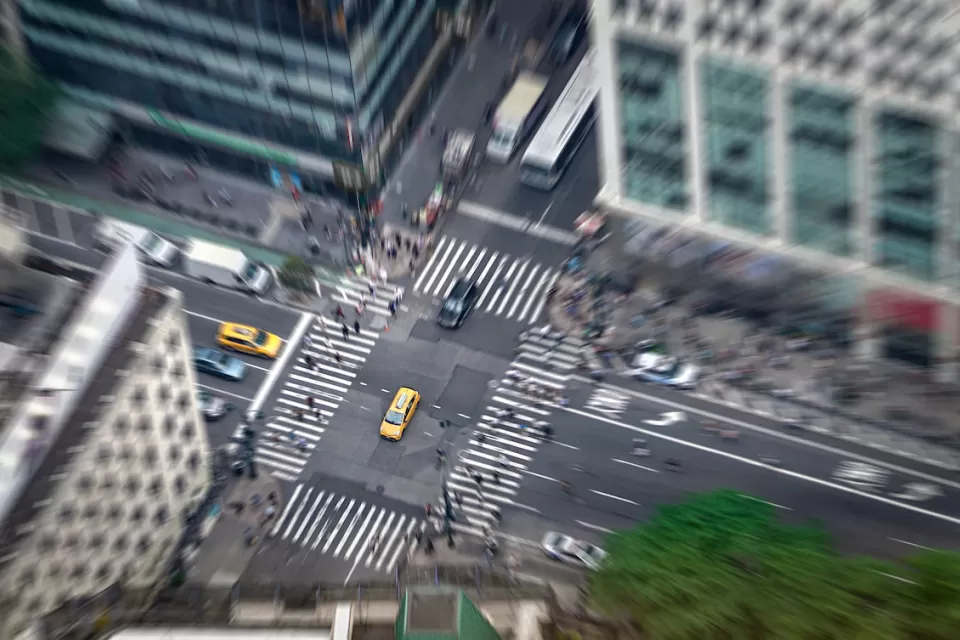 Aerial view of intersection in New York City with yellow cabs and zebra crosswalks.